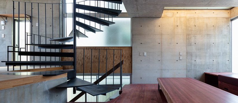 コンクリート壁と螺旋階段と木の仕上げの住宅